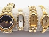 three gold watches are sitting on a napkin on a white surface