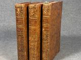 three old books sitting on top of each other on a gray surface