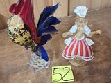 deux figurines représentant un coq et une femme, posées sur une table