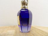 a blue glass bottle with a gold lid on a wooden table