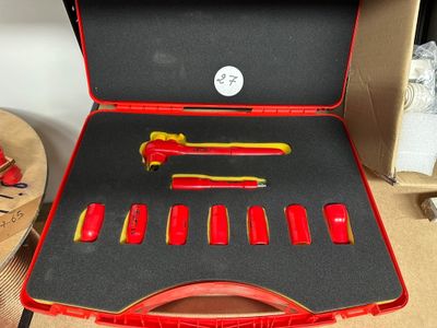 une mallette rouge contenant des outils, posée sur une table