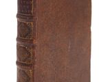 un vieux livre brun posé sur une surface blanche