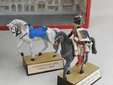 two figurines of a man on a horse and a horse drawn carriage