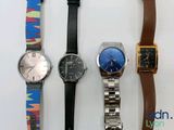 four different watches are lined up on a white surface