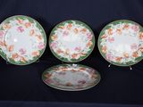 trois assiettes ornées de motifs floraux sont posées sur une surface noire