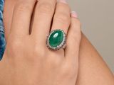 La femme porte une bague sertie d'une pierre verte.
