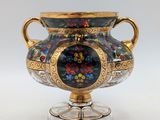 un vase orné d'un motif floral, posé sur un socle