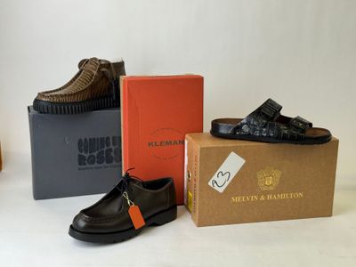 three pairs of men ' s shoes sitting on top of a box