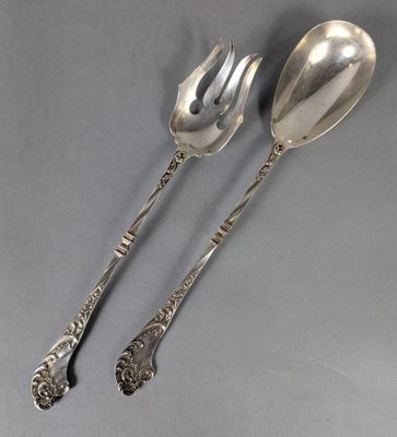 deux cuillères et une fourchette en argent sur une surface grise