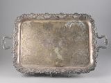 an antique silver tray with handles on a stand on a gray background