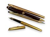 trois types de stylos différents sont alignés sur une surface blanche