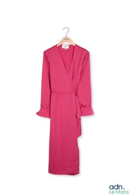 une robe rose à volants suspendue à un cintre sur un mur blanc