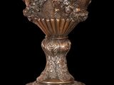 a bronze vase with a clock on it on a black background