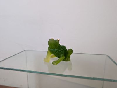 une grenouille en plastique posée sur une table en verre
