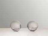 two silver spheres are sitting on a white surface with a gray background