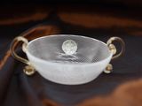 an image of a white bowl with gold handles on a brown cloth
