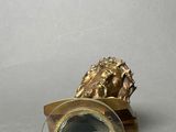 a gold lion figurine with a magnifying glass on a table