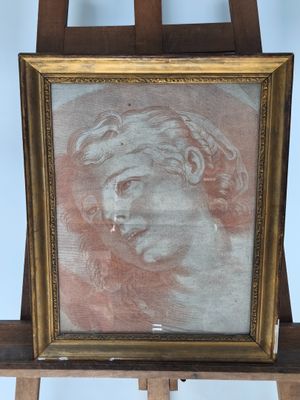 painting of a man ' s head in a gold frame on a wooden easel