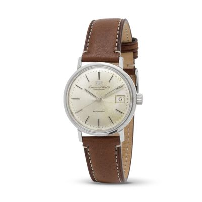 a close up of a watch with a white dial and brown leather strap