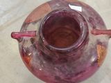 a purple vase with a red handle sitting on a table