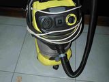 un aspirateur jaune et noir posé sur un sol carrelé