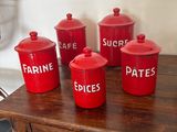 cinq bidons rouges posés sur une table en bois