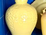 deux vases jaunes posés sur une étagère carrelée de bleu