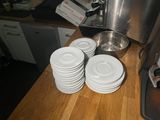 a lot of white plates on the counter next to a coffee maker