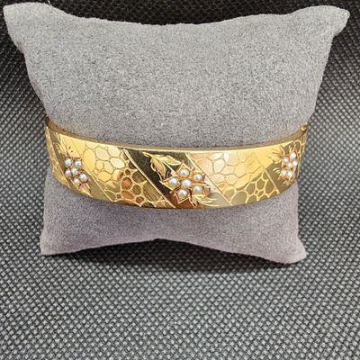 une photo en gros plan d'un bracelet en or posé sur un oreiller