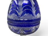 blue glass egg shaped box with a stand on a white surface