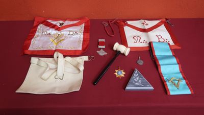 une table recouverte d'une nappe rouge, avec deux tabliers et une paire de ciseaux