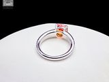 a silver ring with a red stone on top of a white plate
