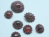 six red glass beads are arranged on a white surface