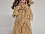 an old fashioned doll with a hat and dress on a white surface