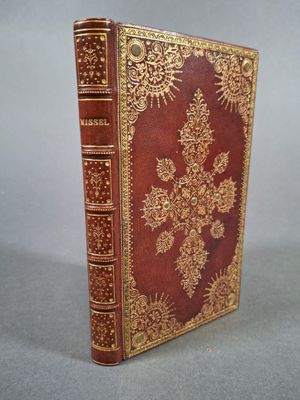 un vieux livre à la couverture dorée et rouge posé sur une table