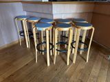 four wooden stools sitting on top of a wooden floor next to a bar