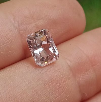 une personne tient un diamant rose dans la main, sur un fond vert