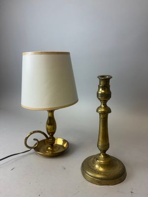 une paire de bougeoirs en laiton et une lampe posés sur une table blanche
