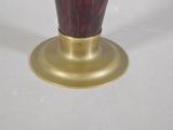 a red vase with a gold base on a white table