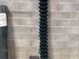 a black wire fence next to a brick wall and a roll of wire