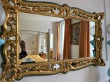 a gold framed mirror hanging on the wall in a living room