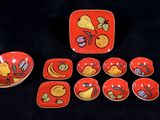 a red plate with a bird design on it next to six bowls and a plate with a bird design on it