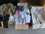 a box full of clothes sitting on the floor next to a pile of boxes
