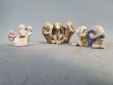 trois figurines de singes posées sur une table, sur fond blanc