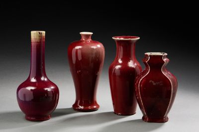 trois vases rouges posés les uns à côté des autres sur une table