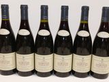 six bouteilles de vin sont alignées sur une table