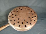 a metal strainer with a wooden handle on a table