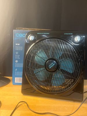 un ventilateur posé sur une table à côté d'une lampe