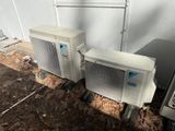 two air conditioners sitting next to each other on the ground