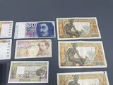 five different bank notes on a table with a clock